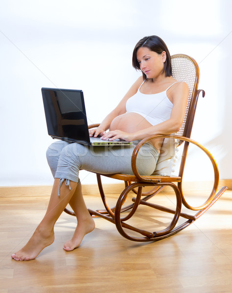 Stock photo: Beautiful pregnant woman at home with laptop