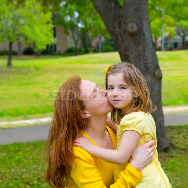 Mother kissing her blond daughter in green park Stock photo © lunamarina