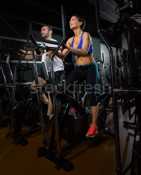 elliptical walker trainer man and woman at black gym Stock photo © lunamarina