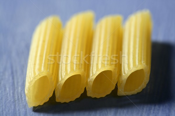 Four yellow macaroni in a line, macro in blue background Stock photo © lunamarina