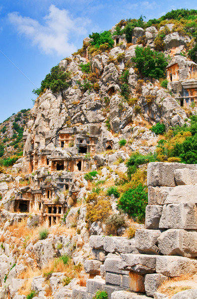 Stock photo: Ancient tombs in the rock high  mountains and fun sun on the sky