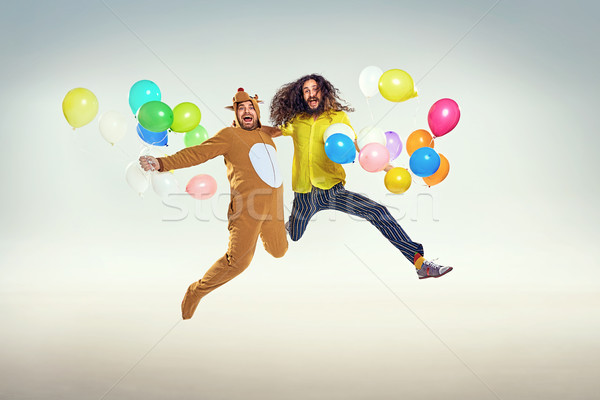 Picture presenting two funny guys jumping and holding balloons Stock photo © majdansky