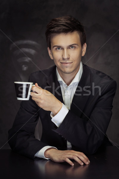 Smart young businessman holding the cup of vaporous coffee Stock photo © majdansky