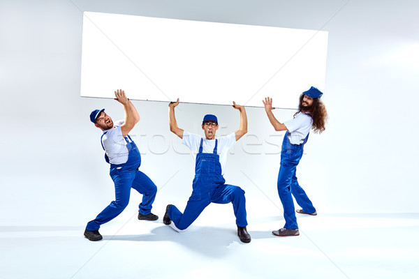 Funny craftsmen lifiting a heavy commercial board Stock photo © majdansky