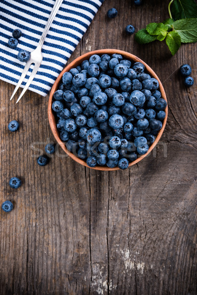 Full bowl of fresh ripe blueberries on old wooden board Stock photo © manera