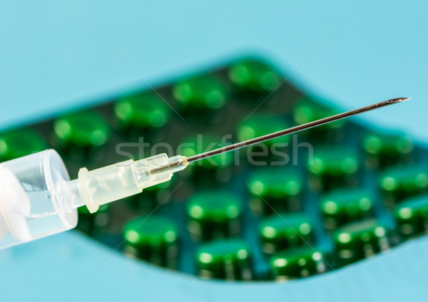 Stock photo: Syringe and a blister pack with tablets