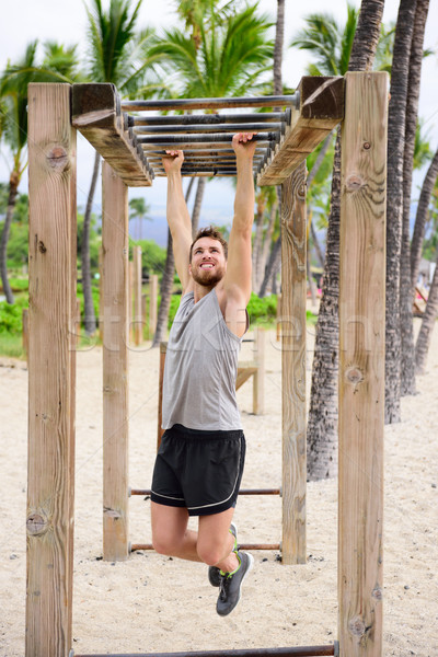 Fitness man on monkey bars fitness station gym Stock photo © Maridav