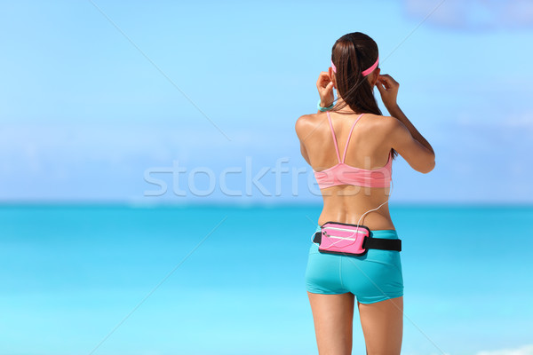 Fitness girl listening to music with earphones Stock photo © Maridav