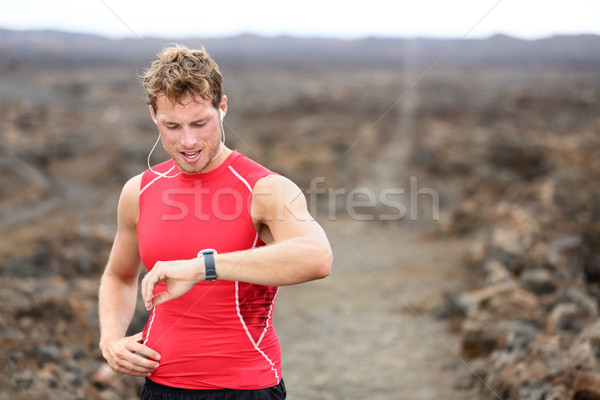 Running athlete man looking at heart rate monitor Stock photo © Maridav