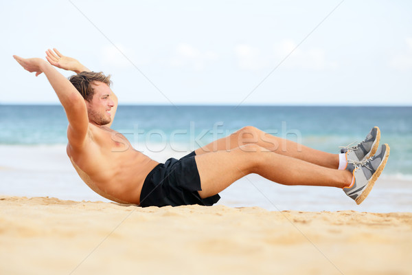 Fitness man doing crunches sit-ups on beach Stock photo © Maridav