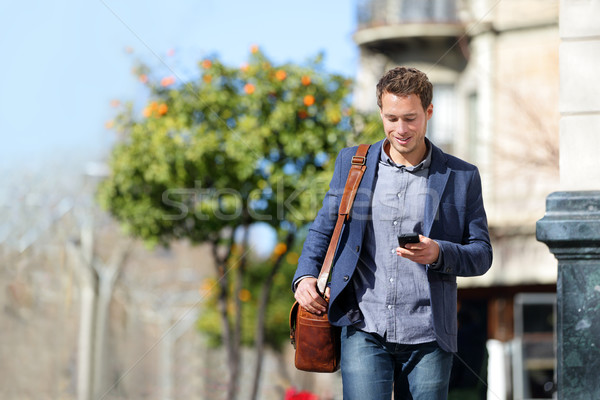 Business man using mobile phone walking to work Stock photo © Maridav