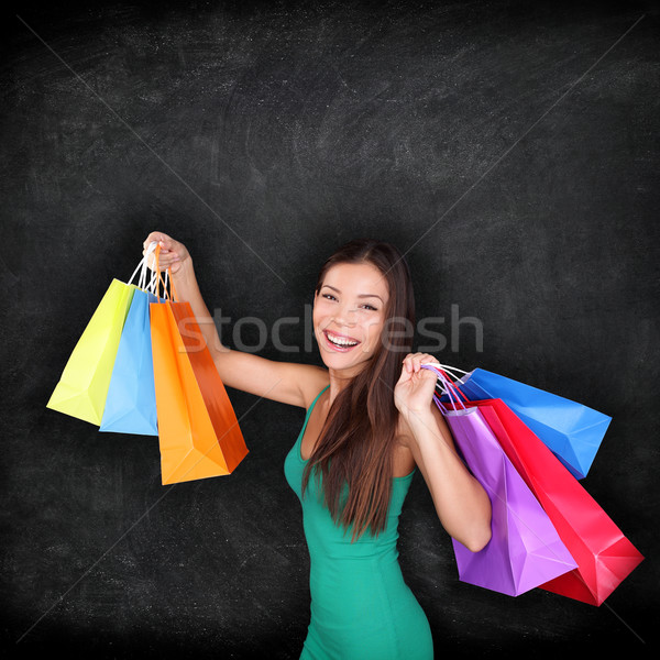 Stock photo: Shopping woman holding shopping bags on blackboard