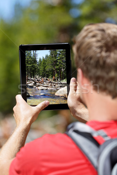 Hiking man taking nature pictures on tablet Stock photo © Maridav