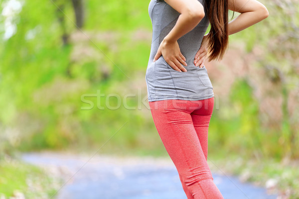 Back pain - Athletic running woman with back injury Stock photo © Maridav