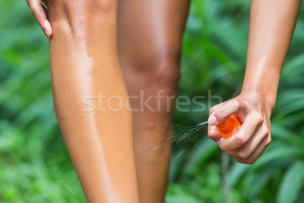Woman spraying mosquito repellent on leg skin Stock photo © Maridav