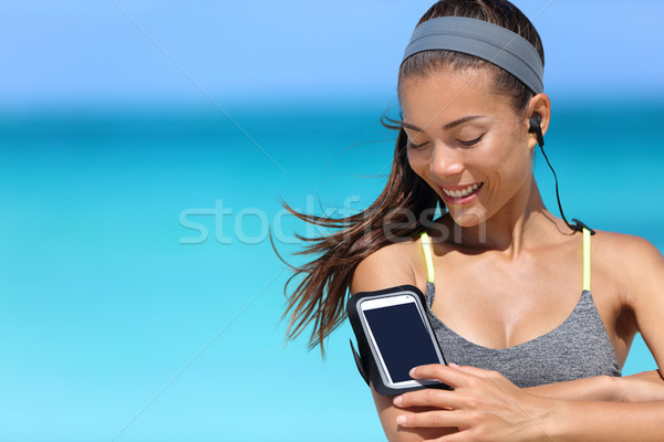 Fit woman using smartphone fitness app on armband Stock photo © Maridav