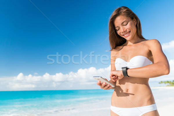 Bikini woman using smart phone syncing watch data Stock photo © Maridav