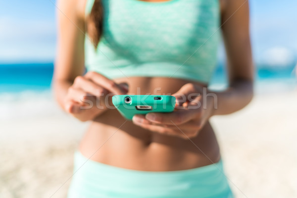 Athlete using fitness app smartphone beach workout Stock photo © Maridav