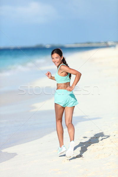 Happy healthy lifestyle woman runner looking back running on beach Stock photo © Maridav