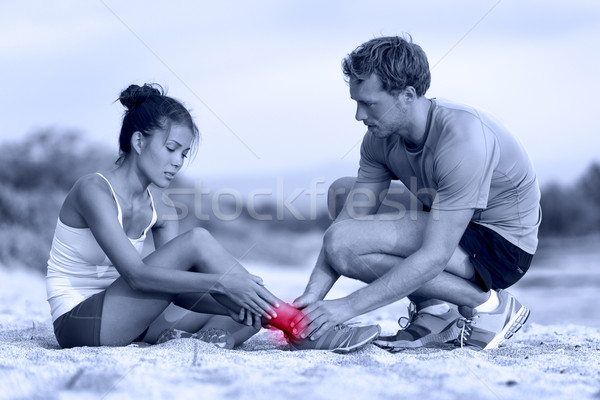 Stock photo: Sprained ankle - trainer helping runner in pain