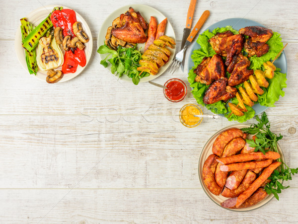 Ebédlőasztal választék étel sültcsirke szárnyak kolbászok Stock fotó © markova64el