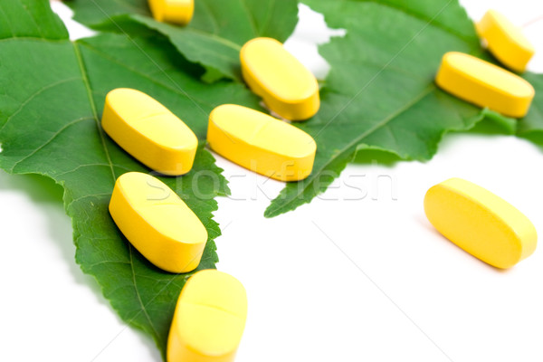 yellow vitamin pills over green leaves Stock photo © marylooo