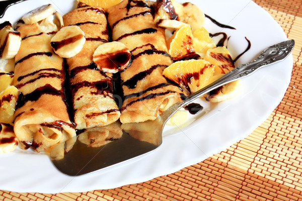 Pancakes stuffed with semolina, bananas and oranges drenched dark chocolate Stock photo © MarySan