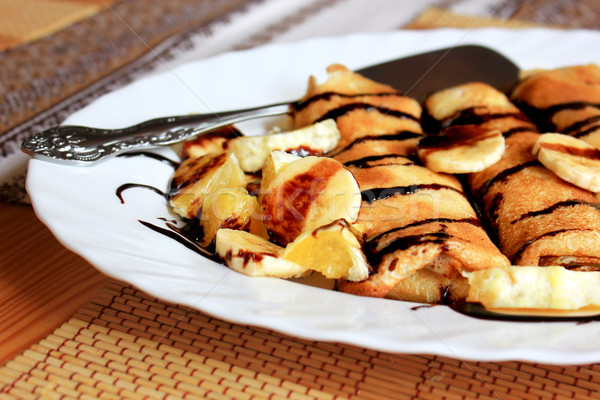 Pancakes stuffed with semolina, bananas and oranges drenched dark chocolate Stock photo © MarySan