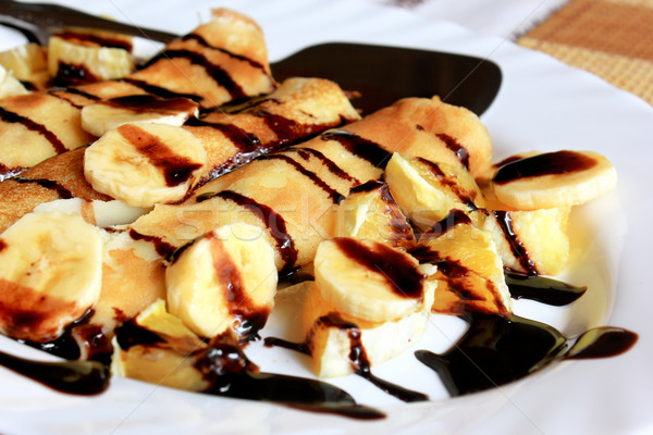 Pancakes stuffed with semolina, bananas and oranges drenched dark chocolate Stock photo © MarySan