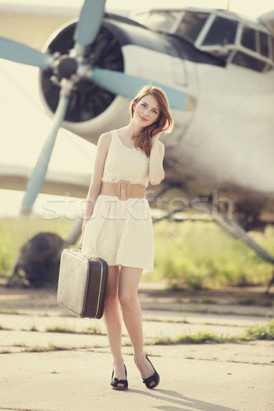 Stock photo: Lonely girl with suitcase at near airplane. 