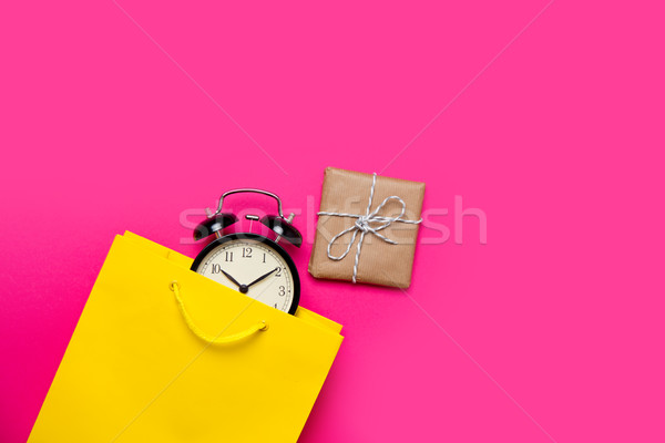 cool black alarm clock in beautiful yellow shopping bag and cute Stock photo © Massonforstock