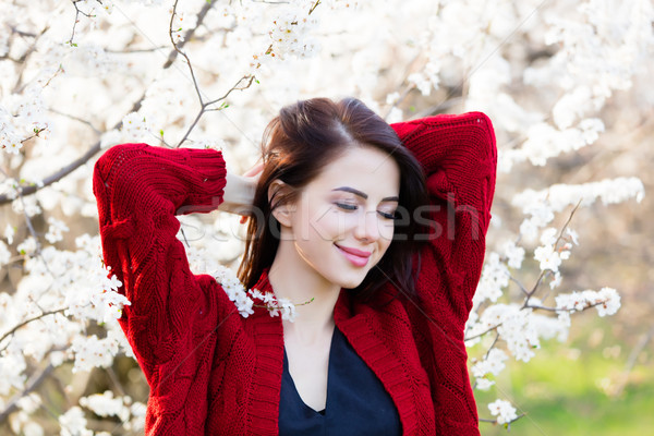 Stock photo: beautiful young woman standing in front of wonderful blooming tr