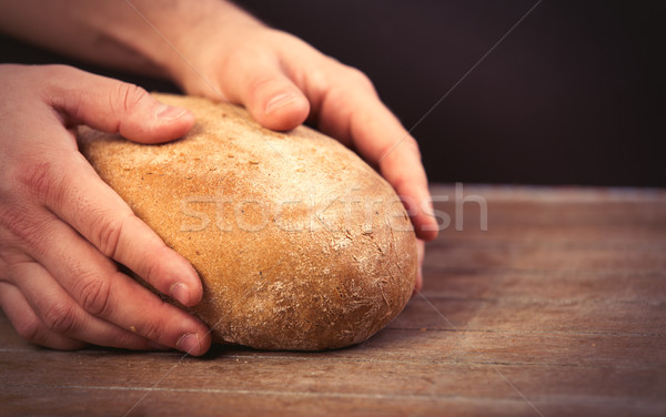 Stock photo: male hands holding bread loaf on the wonderful brown wooden back
