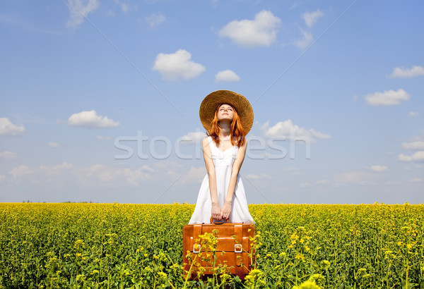 Redhead enchantress with suitcase at spring rapeseed field. Stock photo © Massonforstock