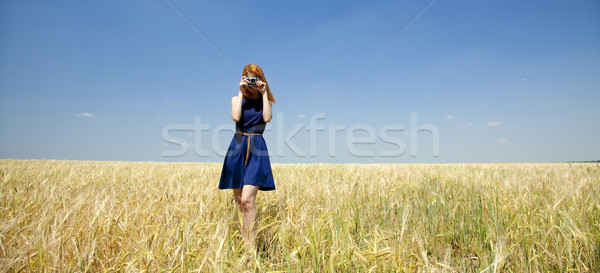 Stock photo: Redhead girl at spring field with retro camera.