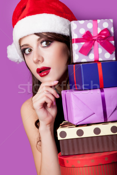 photo of beautiful young woman with gifts in santa claus hat on  Stock photo © Massonforstock