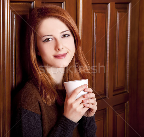 Stock photo: Style redhead girl drinking coffee near wood doors.