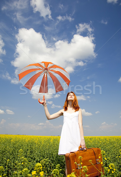 Redhead enchantress with umbrella and suitcase at spring rapesee Stock photo © Massonforstock