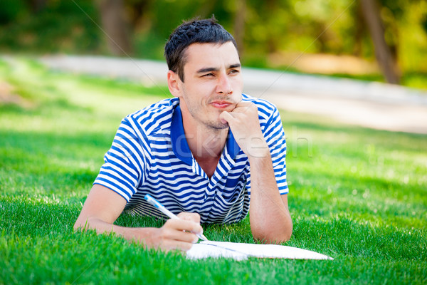photo of handsome man lying on the grass and thinking about some Stock photo © Massonforstock