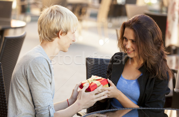 The young man gives a gift to a young girl in the cafe Stock photo © Massonforstock