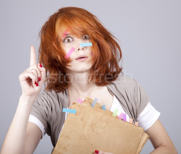 Stock photo: Red-haired businesswoman with book and notes on face. 