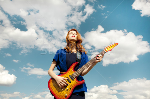 Redhead girl with guitar at sky background. Stock photo © Massonforstock