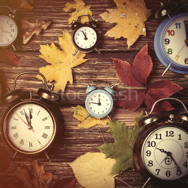 Autumn leafs and alarm clock on wooden table. Stock photo © Massonforstock