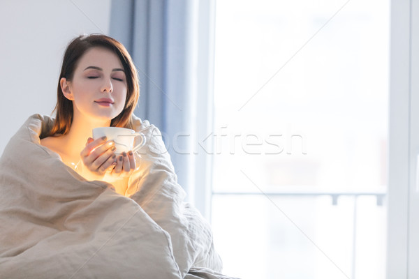 Beautiful rednead woman with cup of coffee or cappuccino in a be Stock photo © Massonforstock