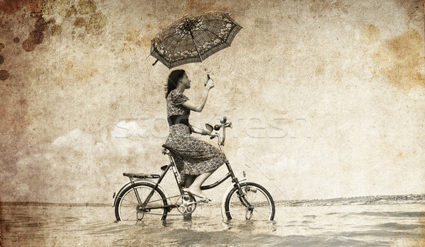 Girl with umbrella on bike. Photo in old image style.  Stock photo © Massonforstock