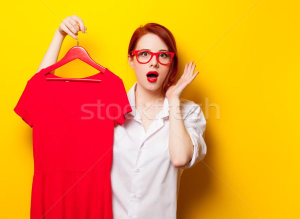 Stock photo: photo of beautiful young woman holding shirt on hanger on the wo