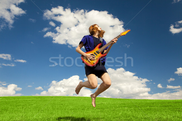 Redhead girl jumping with guitar at outdoor. Stock photo © Massonforstock