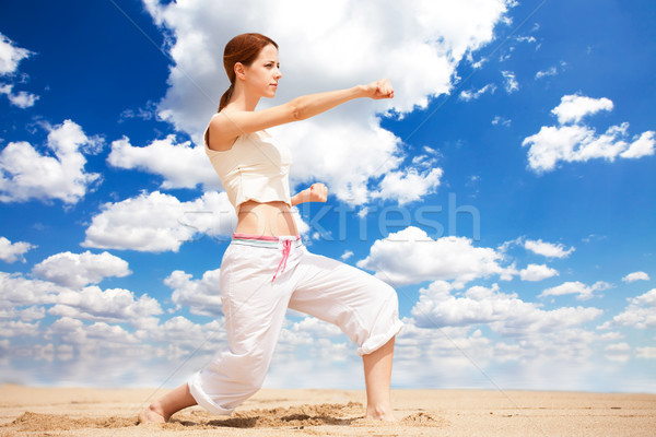 athletic woman performing a kick in an sand beach Stock photo © Massonforstock