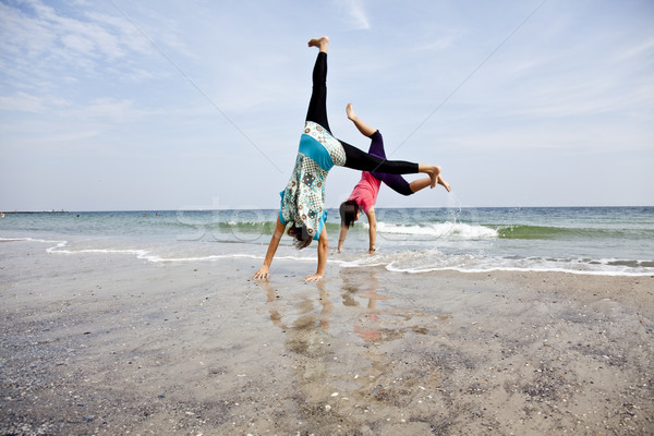 Young girl show an acrobatic on the beach. Stock photo © Massonforstock