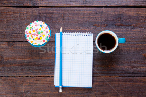 Stock photo: photo of notebook with pencil, cup of coffee and cupcake on the 